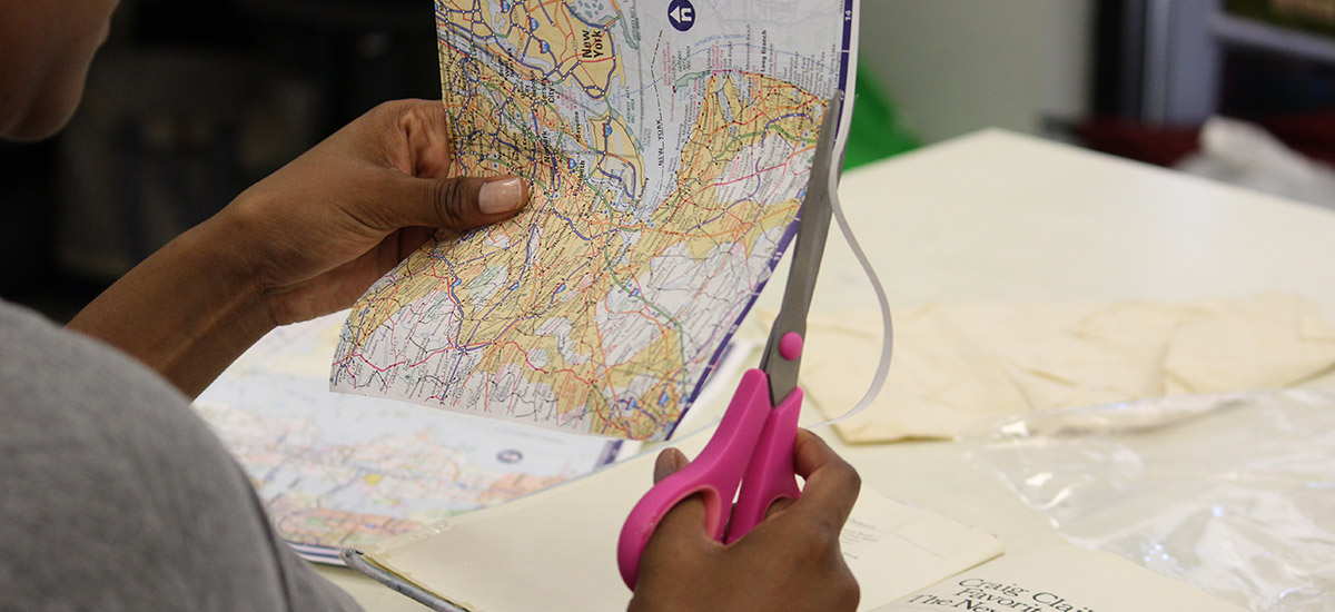 person cutting a map as part of book making project