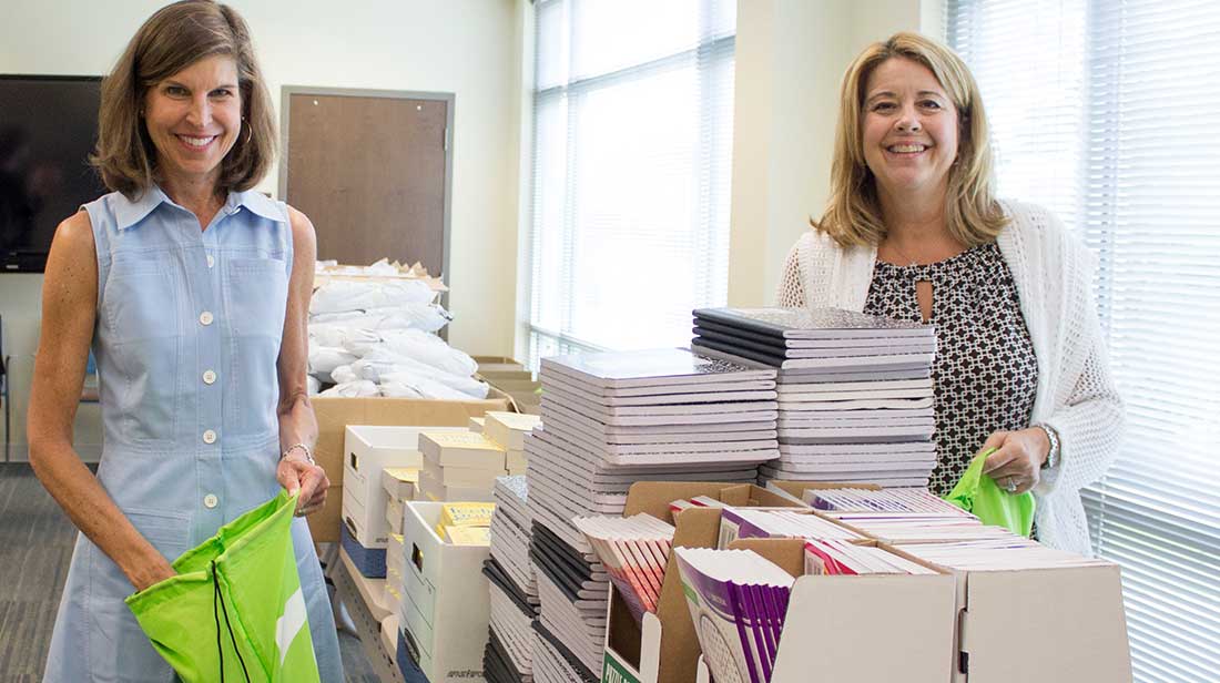 two women associates members putting items in residential client welcome bags