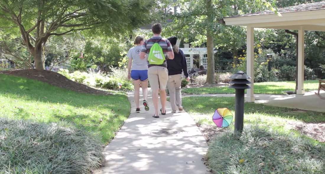 three adults walking on a path with a back pack