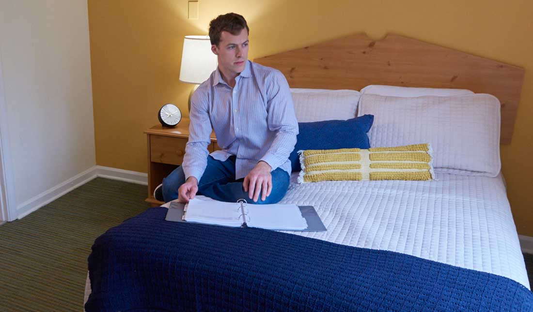 man sitting on bed in residential treatment bedroom