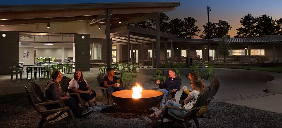 five college age adults sitting around a fire pit