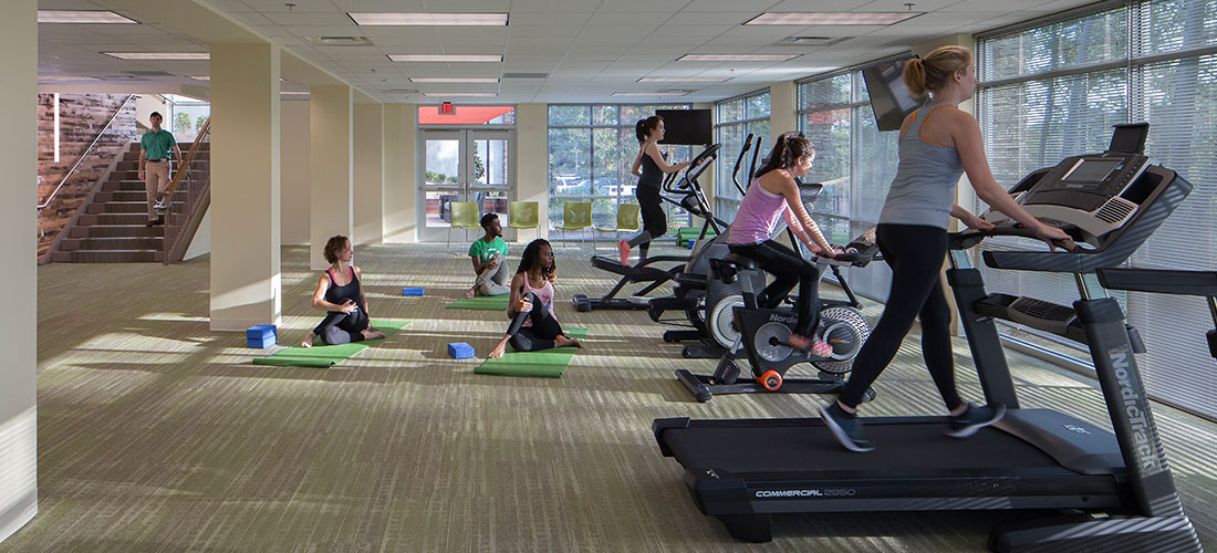 adults on exercise equipment and stretching on mats on the floor