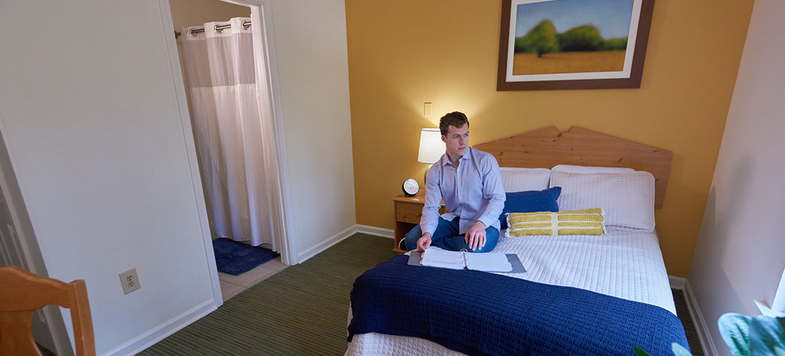 person sitting on bed in private client bedroom