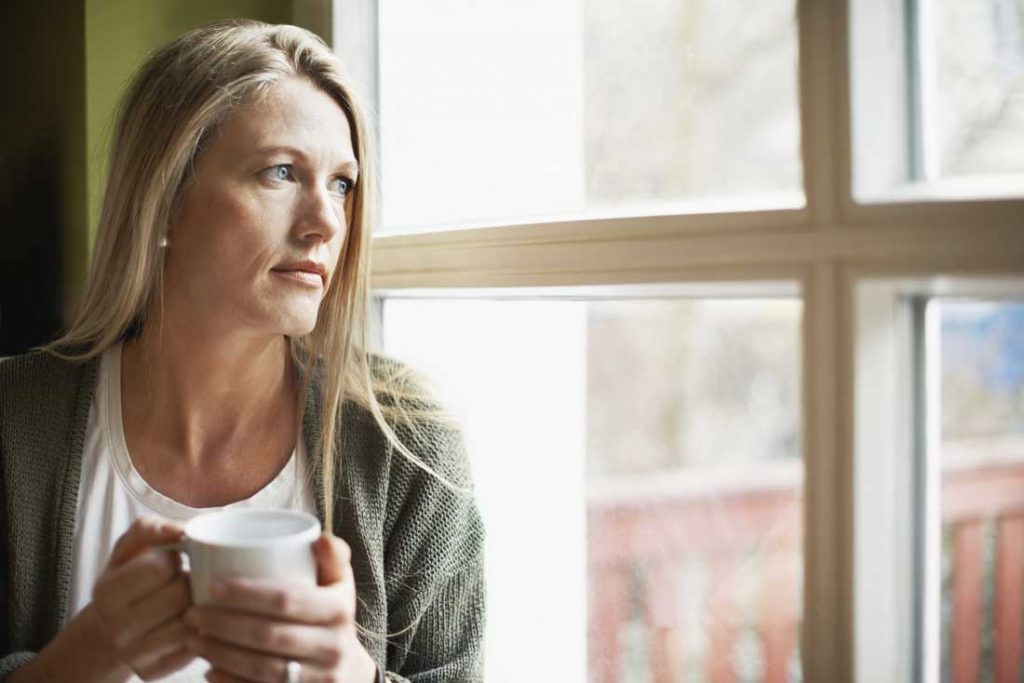 woman holding a mug looking out the window