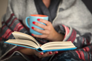 a woman reading a book with a cup of tea