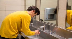 Teen with OCD washing hands at sink