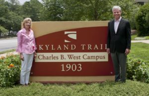 Margie Wynne and Mark West in front of monument sign for Charles B West Campus in 2014