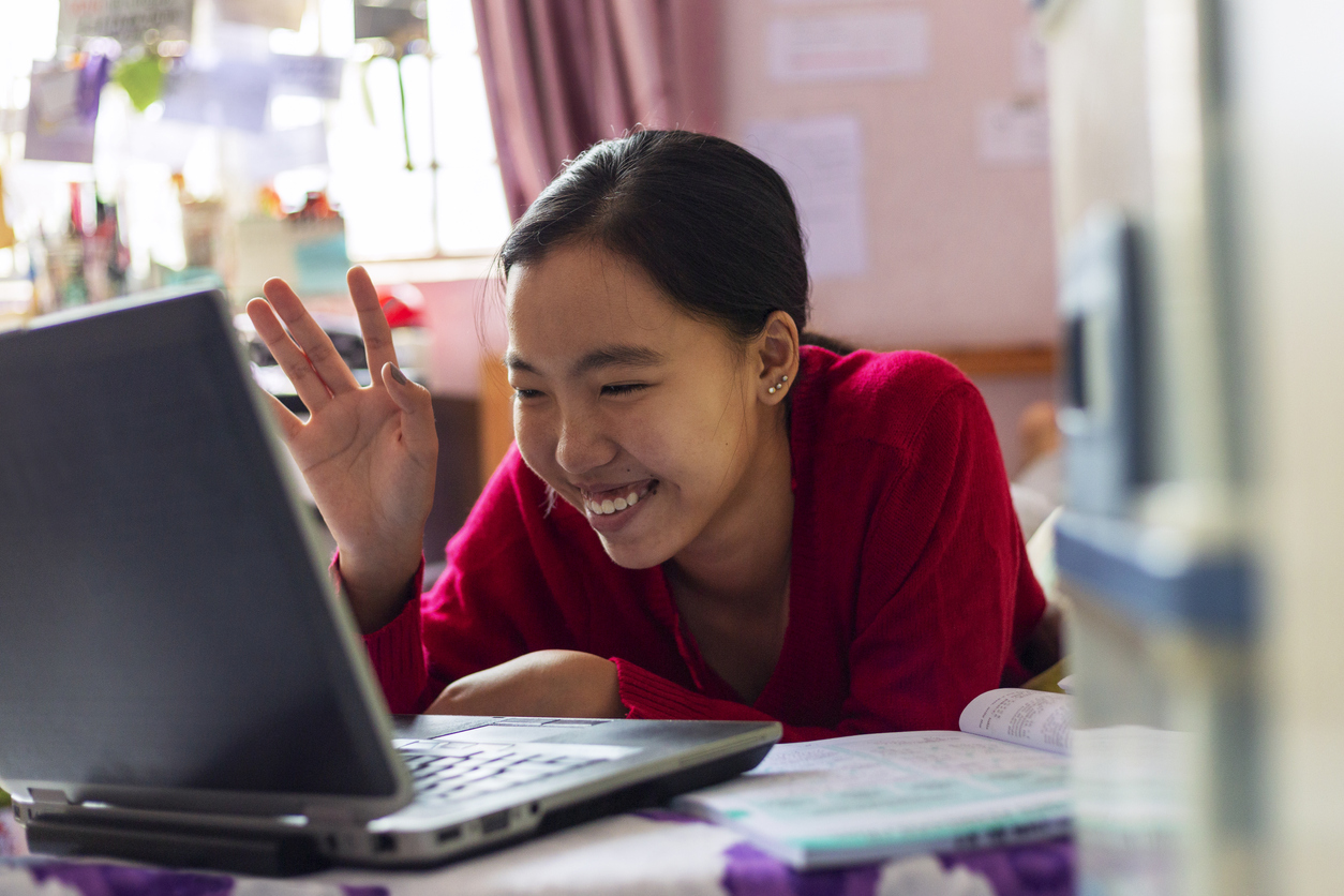 Young Girl Uses Her Laptop Teleconferencing In The House Asian teenage girl having video call with teacher for home schooling using laptop