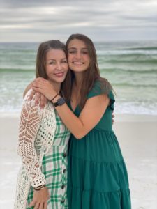 mom with adult daughter hugging on the beach