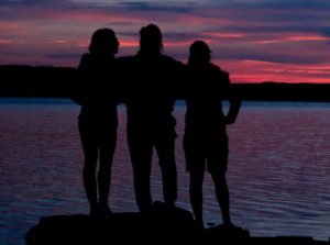 silhouette of three adults at the beach at sunset