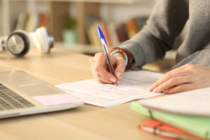 teen completing test on paper sitting at a desk