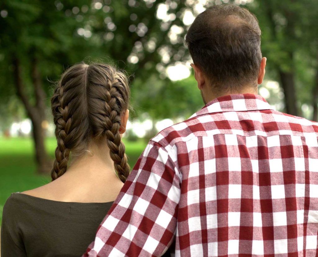 father with arm around teen daughter