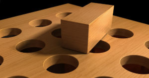 an image of a wooden square block on top of a piece of wood with round holes to signify putting a square peg in a round hole.