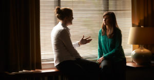 Two people sit in near one another as they share a conversation