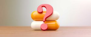 two psychiatric medication capsules stack vertically with a question mark in front