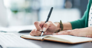 Close-up of a hand holding a pen and writing in a notebook