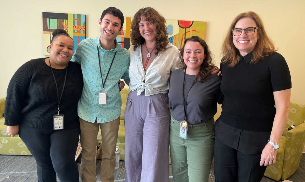 group of five smiling adults standing in a group therapy room at a mental health treatment facility