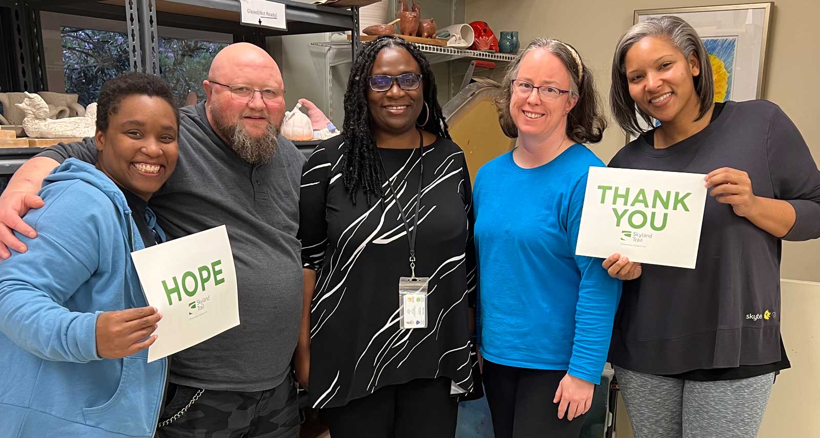 5 adults standing in a row, holding a sign that says, "hope," and another sign that says "thank you"