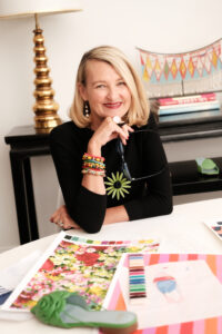 Elyce Arons photo of Elyce Arons smiling in front of pages of color swatches