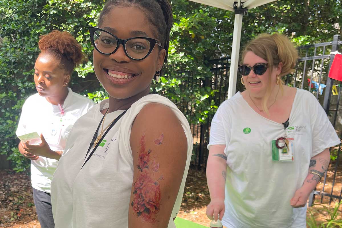 arts-in-the-garden-fun young woman smiling and showing temorary tatoo of roses on her arm