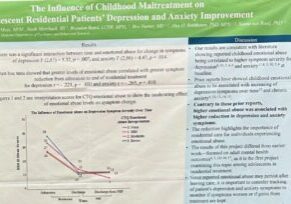 Woman with glasses stands next to research poster with graphs