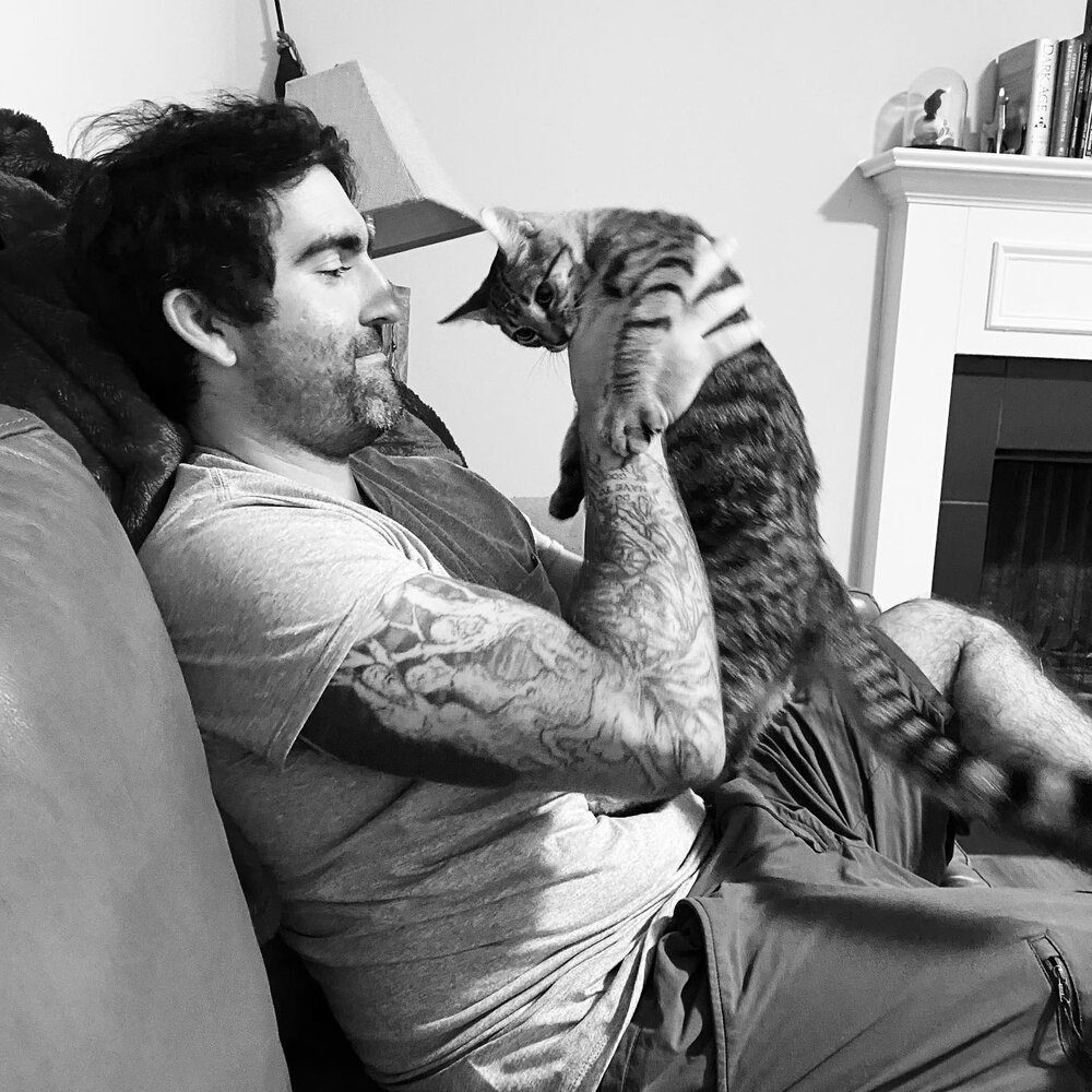 man sitting on couch holding Cat