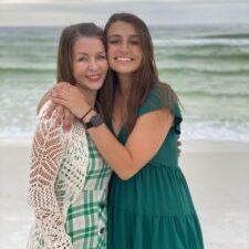 mom with adult daughter hugging on the beach