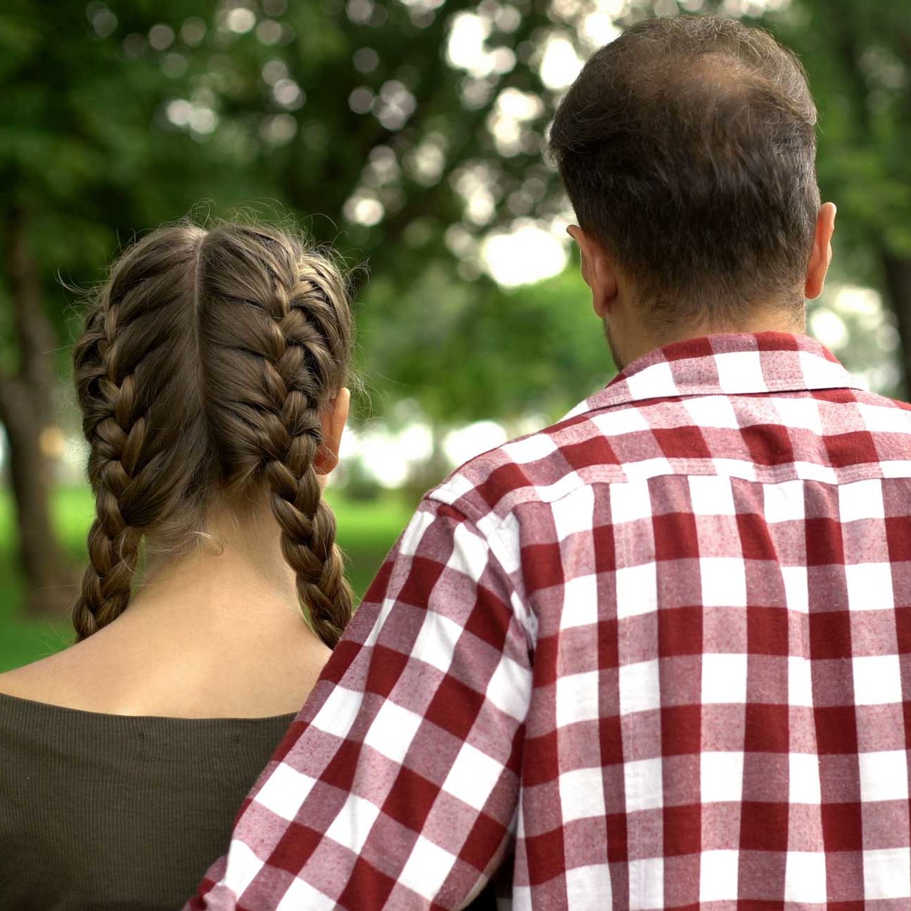 father with arm around teen daughter